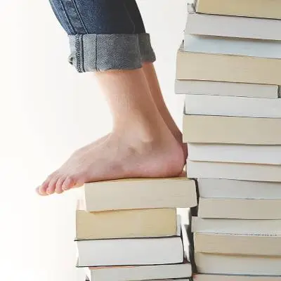 Bare foot stepping on a stack of books, representing foot health and everyday balance